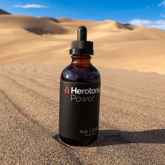 Black tincture bottle on the sand with the view of sand dunes in the background